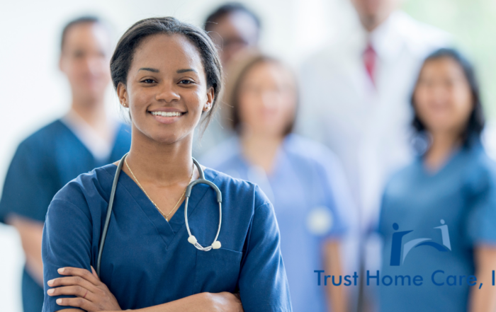A smiling nurse stand with other nurses and professionals in the background.