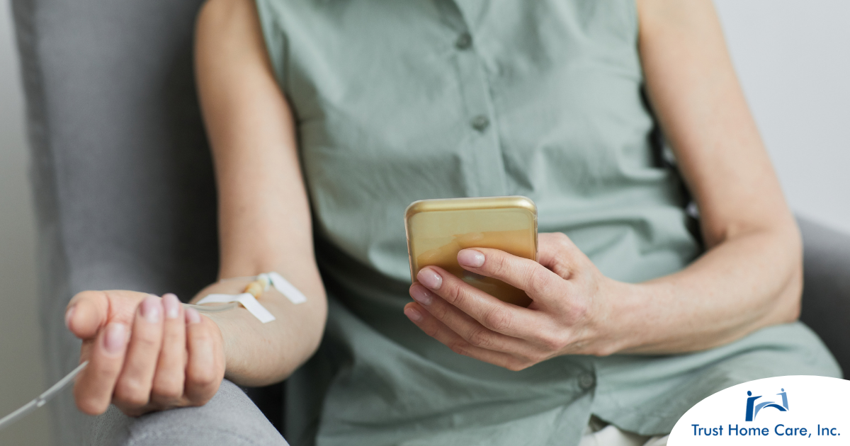 A woman comfortably receives IV therapy at home while using her phone.