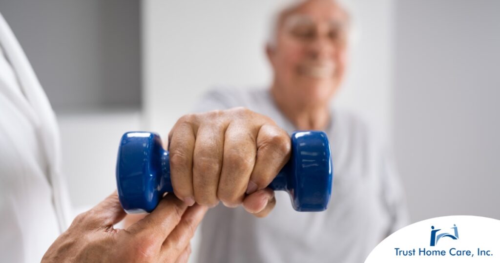 An older man is helped to lift a weight as part of physical therapy.