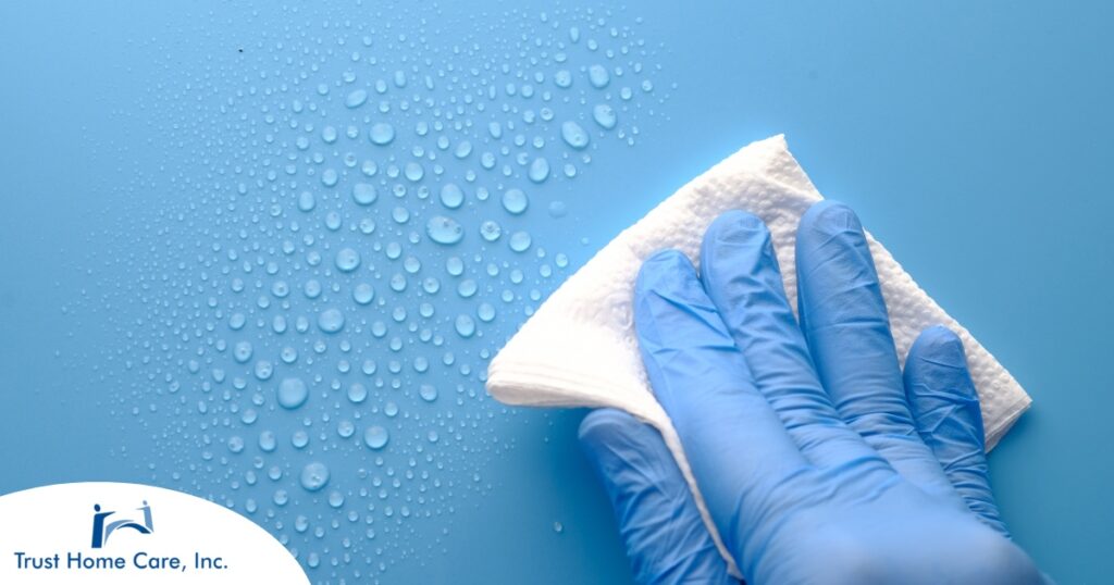 A gloved hand wipes down a surface, representing hygiene and practices that home health workers should employ.