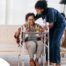 A care professional helps an older woman get up with the use of a walker, representing how occupational therapy can help with recovery.