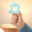 A hand holds up a cutout of a home with a heart in it, representing the home care industry.
