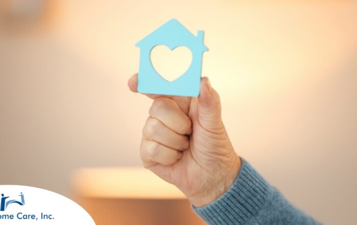 A hand holds up a cutout of a home with a heart in it, representing the home care industry.