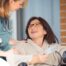 A care provider helps a patient in a wheelchair representing the benefits of medical care at home.