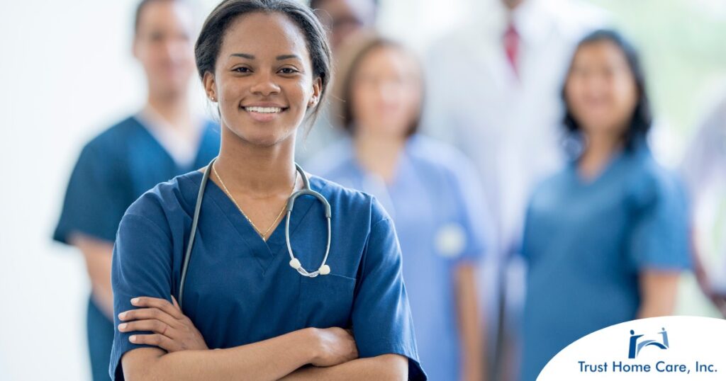A woman in scrubs with a healthcare team behind her represents starting a new home health care job with a confident approach.