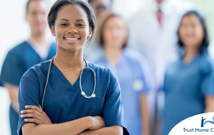 A woman in scrubs with a healthcare team behind her represents starting a new home health care job with a confident approach.
