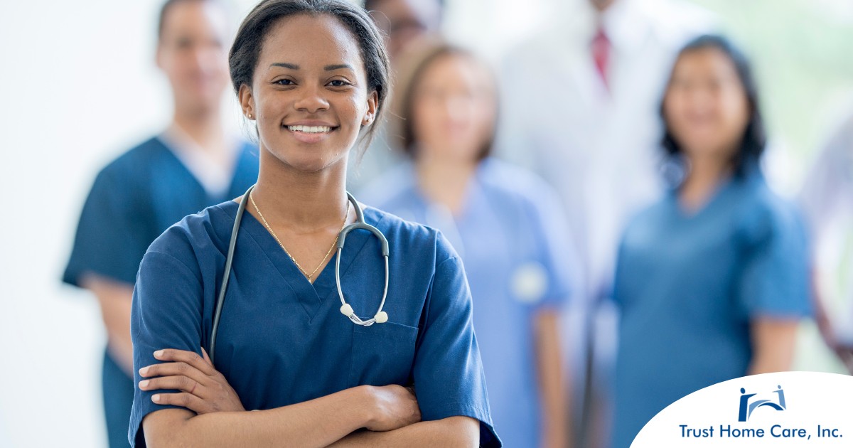 A woman in scrubs with a healthcare team behind her represents starting a new home health care job with a confident approach.