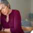 A woman holds her head in her hand, representing the stress that new family caregivers go through.