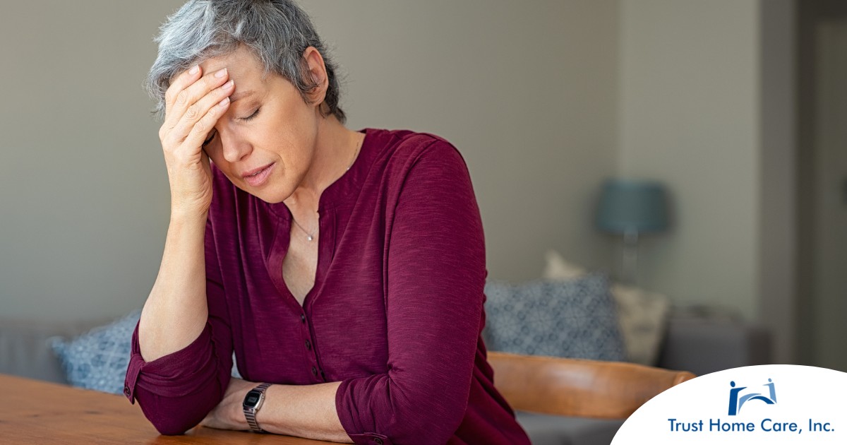 A woman holds her head in her hand, representing the stress that new family caregivers go through.