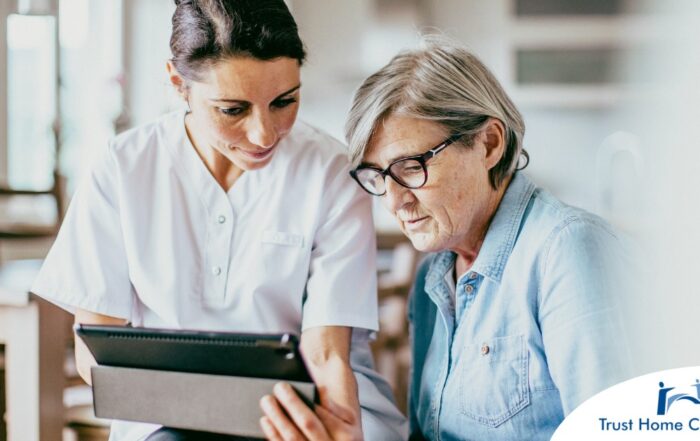 A nurse helps an older patient by showing her a tablet representing the role of tech in registered nurses’ roles in care.