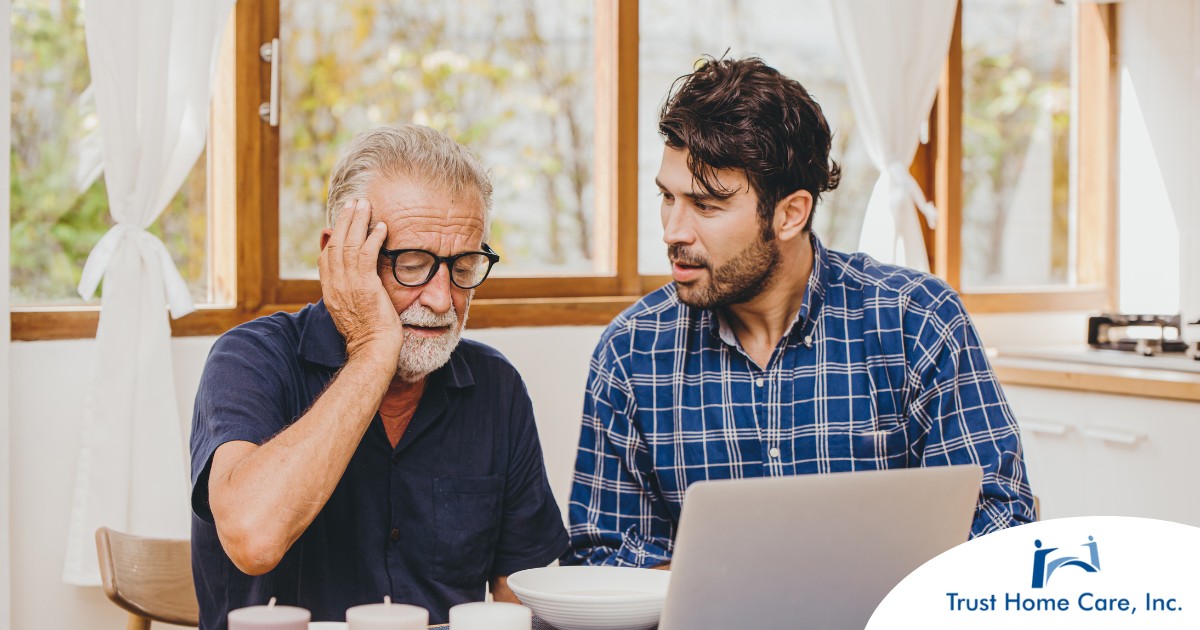 A man looks at a computer with his father who is confused, representing one of the early signs of dementia.
